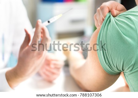 Doctor giving patient vaccine, flu or influenza shot or taking blood test with needle. Nurse with injection or syringe. Medicine, insulin or vaccination. Hospital office room.