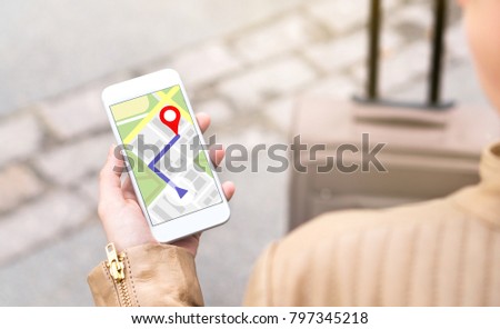 Woman navigating with mobile phone map application. Tourist with walking route on smartphone screen. Traveler with baggage using GPS to find destination or hotel on vacation.