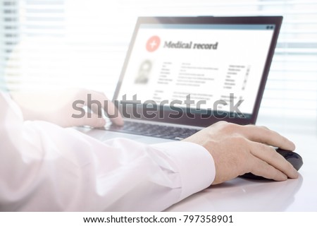 Doctor using laptop and electronic medical record (EMR) system. Digital database of patient\'s health care and personal information on computer screen. Hand on mouse and typing with keyboard.