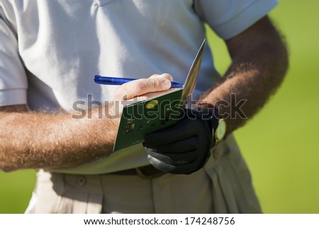 Golf Player Writing The Results In His Notebook