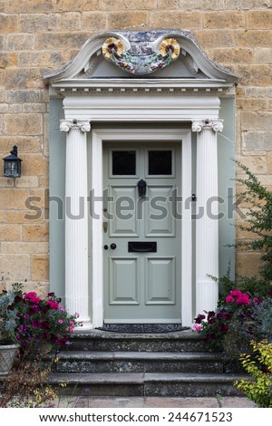richly decorated wooden front door with pillars placed in a limestone facade