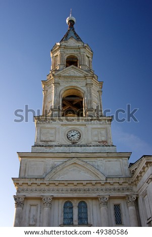 high bell tower of white church on evening light