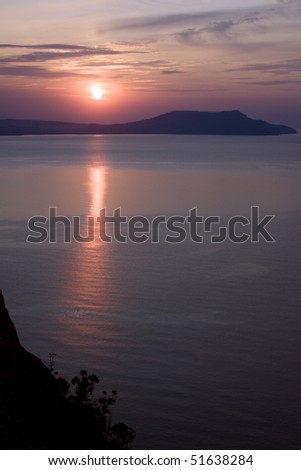 Morning on sea coast, red sun is reflected in water