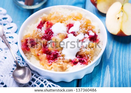 Creamy rice pudding with apple, raspberry and cinnamon. Dessert made from rice, milk, eggs, vanilla and sugar.
