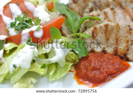 grilled turkey with salad and homemade red pepper pasta on white plate