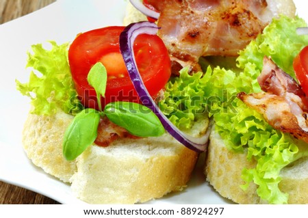 sandwich with bacon, lettuce and tomatoes on black plate