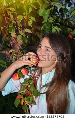 Beautiful girl eats apples that grow on the tree