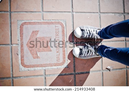 Male sneakers on the asphalt road with drawn direction arrow