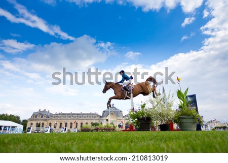 CHANTILLY, FRANCE - JULY 26, 2014: A rider competes in the Longines Global Champions Tour Grand Prix (Class 04) before the 18th century stalls of Chantilly.