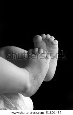 Beautiful baby girl lying down with feet up black and white