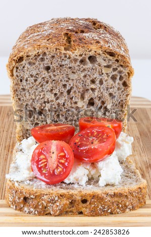 Closeup of slice of wholemeal bread with cottage cheese and cherry tomatoes