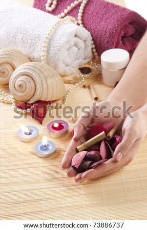Spa essentials and skin care items with candle and sea shells on bamboo
