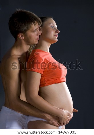 The man and woman with child standing against black background