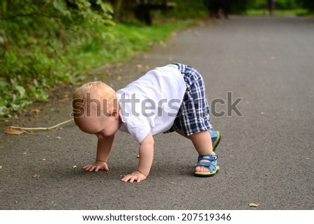 boy stands on all fours in the alley in the park