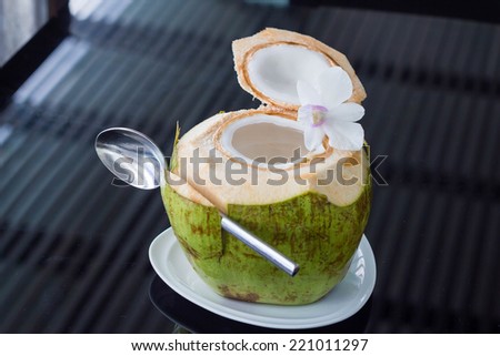 Coconut water is on the table with flowers in it.