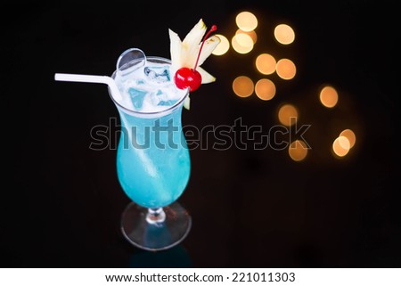 Blue cocktail with cherry and pineapple in it.