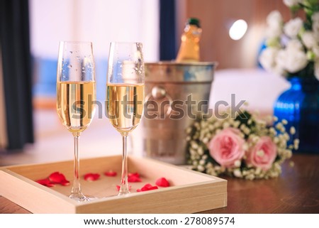 Two glasses of champagne with ice bucket and red roses