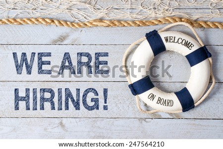 We are hiring ! - Welcome on Board - Lifebuoy with fishnet and blue text on wooden background