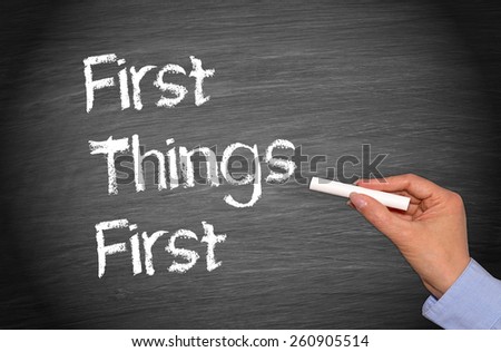 First Things First - female hand writing text on chalkboard
