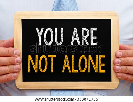 You are not alone - Businessman holding chalkboard with text