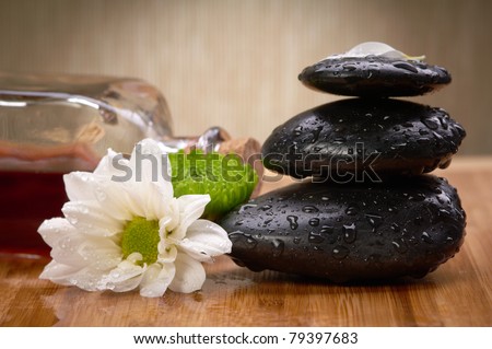 black balanced stones, flower and essential oil bottle