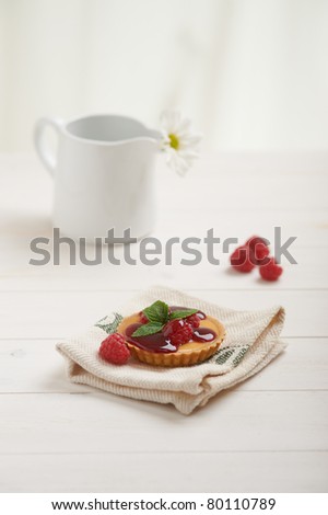 raspberry tart on a napkin, in background white flower
