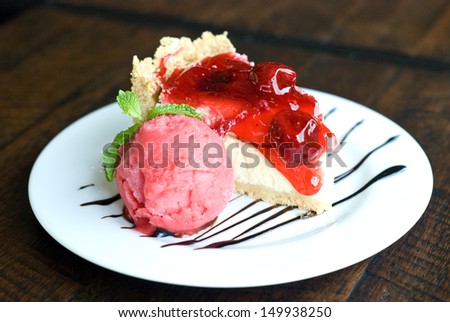 horizon view of portion of strawberry cheese cake and strawberry ice-creme on white plate topping with chocolate sauce