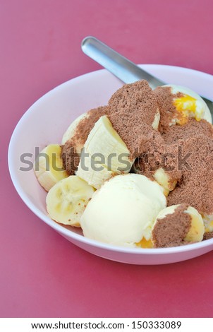 scoops of vanilla ice cream with banana topping with cocoa or chocolate powder