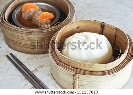 close up Chinese bun and yolk dim sum in wooden steamer on white stone table