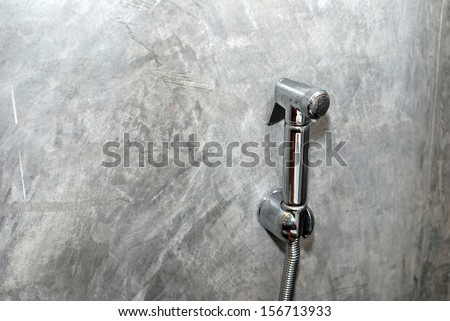 Faucet water sprayer on grunge wall