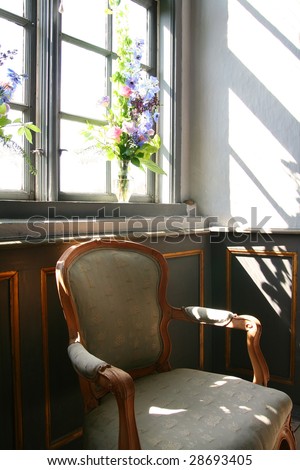 antique armchair in front of window with flowers in background in manor house