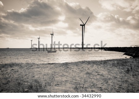  beach with windmills producing renewable electric power - stock photo