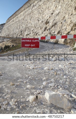 warning sign unstable cliffs. path closed by ravine of falling rocks and stone from hill due to erosion