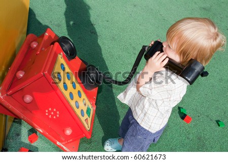 child on play toy telephone. blond kid outside playing game of pretend communication