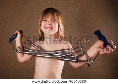 Child exercise with gym equipment. studio image of boy with spring coil fitness device on brown studio background