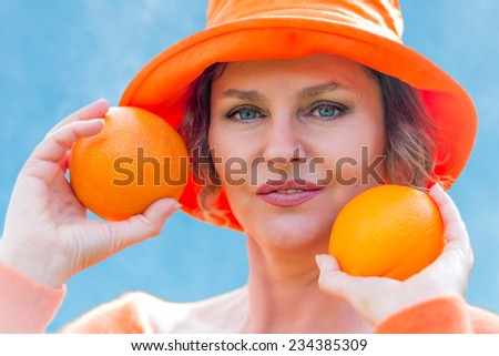 Woman in orange hat  holding a two oranges