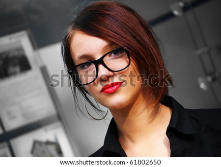 Beautiful businesswoman with glasses and red lipstick.Monochrome office  background.