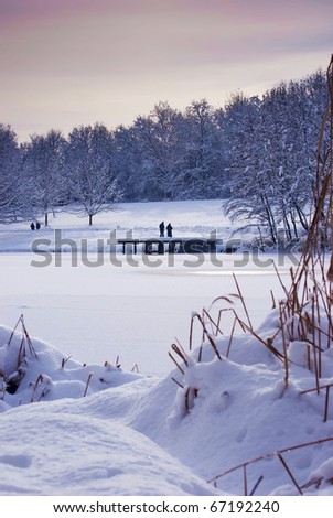 Winter landscape with  frozen lake and a people on the deck in background in background.