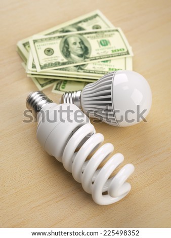 CFB and LED lamps in front of one hundred dollar bill stack
