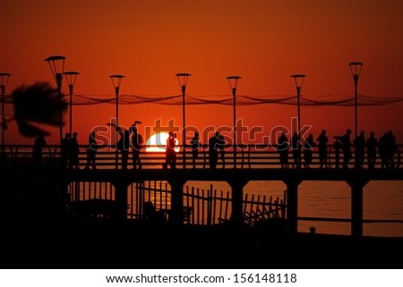 Pier with people relaxing by the sunset