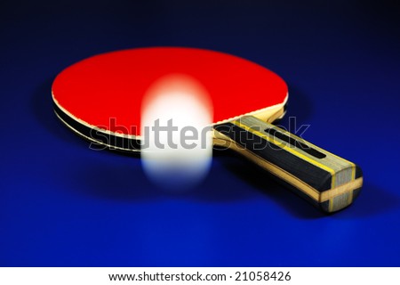 Table tennis racket and jumping ball on blue table