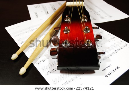 Blues time. Guitar headstock and drum sticks closeup against a blues sheet music.