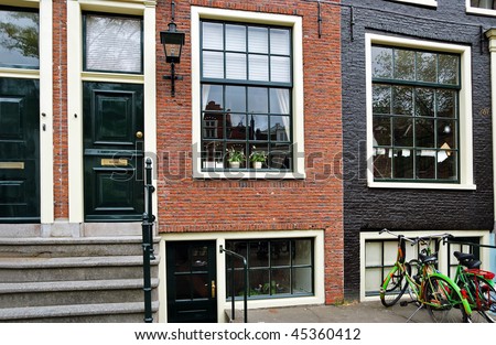 Fragment of a traditional redbrick house in Amsterdam with large clean windows and bicycles nearby