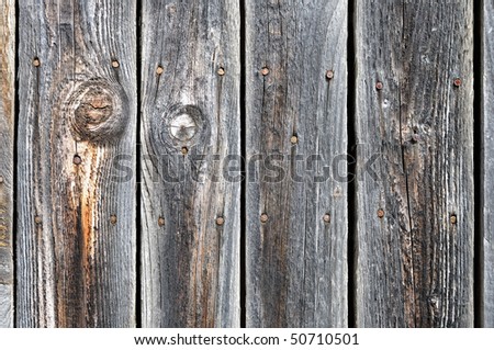 Black painted weathered wooden fence with rusty nail heads