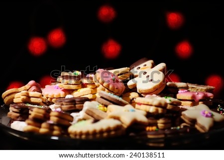 Lots of Christmas cookies and cakes against the background of blurred warm red lights