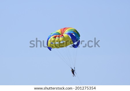 Girl flying in a blue sky on a colorful, multi-colored parachute