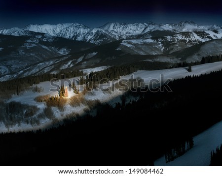 A brightly lit Christmas tree glows with warm light and the Christmas spirit on a cold winter night in the Colorado Rocky Mountains.