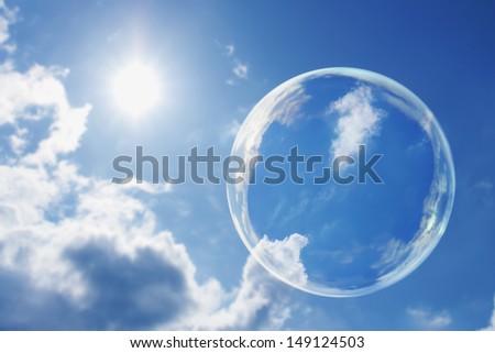 This large soap bubble floats calmly against a clear deep blue sky and clouds representing a natural \'Thought Bubble\' on possible ideas for clean atmosphere, fresh air and a green environment.