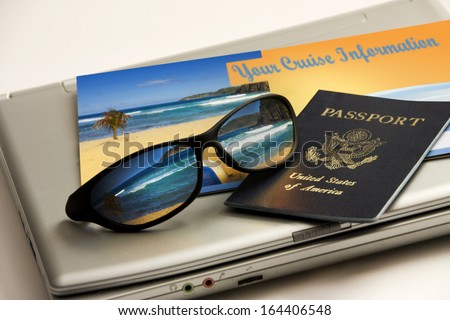 Sunglasses reflect an exotic Caribbean beach vacation with passport, cruise information and travel laptop against a white backdrop. All elements including brochure my own.