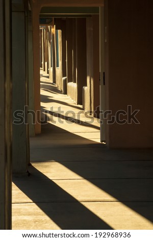 This strong sunlight of this Santa Fe New Mexico morning highlights the strong textures and shadows of the adobe buildings lining the street in the historical downtown plaza.